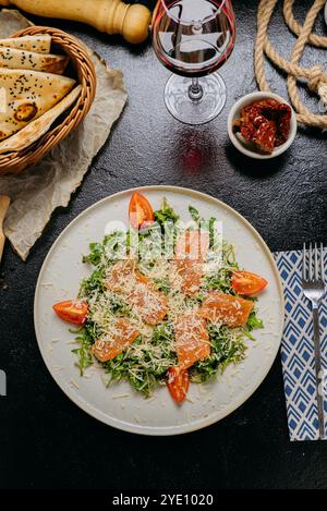 Rucola-Salat mit Räucherlachs, Kirschtomaten und frisch geriebenem Parmesan, serviert mit Rotwein Stockfoto