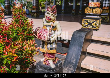 Farbenfrohe Statue eines Musikers, der eine Kendang-Trommel spielt, verleiht der ruhigen Atmosphäre des Tanah Lot-Tempels auf Bali einen Hauch lokaler Kultur Stockfoto