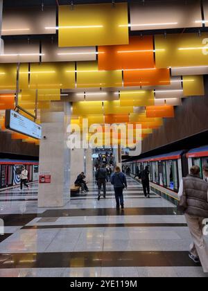 Innenraum der U-Bahn-Station Nowatorskaja an der Bolschaja Koltsewaya-Linie (BKL) der Moskauer U-Bahn, mit orangefarbenen und gelben Tafeln von der Decke Stockfoto