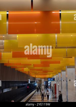 Innenraum der U-Bahn-Station Nowatorskaja an der Bolschaja Koltsewaya-Linie (BKL) der Moskauer U-Bahn, mit orangefarbenen und gelben Tafeln von der Decke Stockfoto