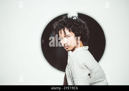 Porträt eines jungen asiatischen Mannes mit lockigen Haaren und Schnurrbart, der selbstbewusst in die Kamera schaut. Das Motiv trägt ein leichtes, lässiges Hemd mit Stockfoto