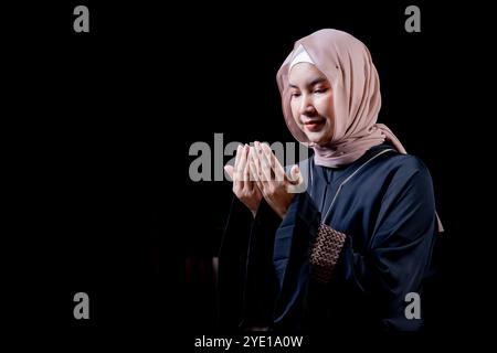 Das Bild einer asiatischen muslimischen Frau in der islamischen Religion in Hijab in cremefarbener Farbe. Sie betete in einer wunderschönen Moschee aus Respekt vor Gott. Stockfoto