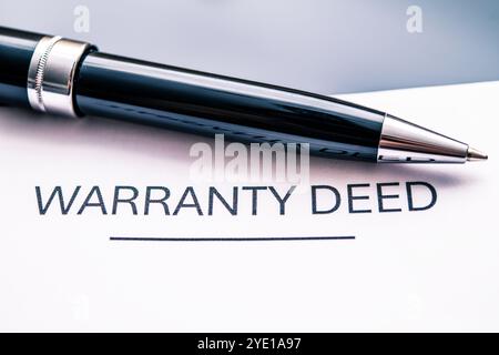 Nahaufnahme eines Garantieurkunden, in dem wesentliche Elemente der Eigentumsübertragung und des rechtlichen Eigentums dargestellt werden. Der Stift symbolisiert die Bestätigung der Immobilie Stockfoto
