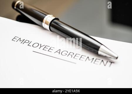 Ein Nahbild eines Dokuments mit Mitarbeitervereinbarung mit einem eleganten schwarzen Stift, das Arbeitsverträge, HR-Richtlinien, rechtliche Vereinbarungen und Geschäftsabschlüsse symbolisiert Stockfoto