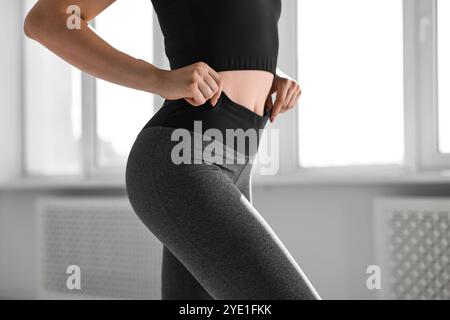 Frau trägt graue Sportleggings drinnen, Nahaufnahme Stockfoto