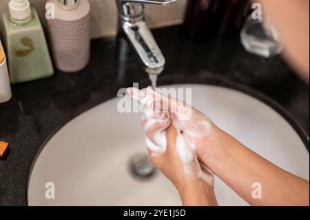 Eine Nahaufnahme einer Frau, die ihre Hände am Waschbecken wäscht und ihre Hände mit Seife reibt. Hygiene, Körperpflege, Bild mit Kopierraum Stockfoto