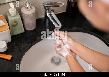 Eine Nahaufnahme einer Frau, die ihre Hände am Waschbecken wäscht und ihre Hände mit Seife reibt. Hygiene, Körperpflege, Bild mit Kopierraum Stockfoto