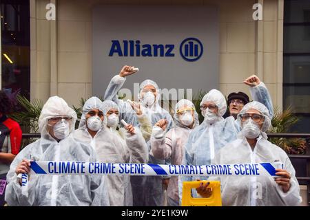 London, Großbritannien. Oktober 2024. Aktivisten in Gefahrenanzügen halten ein „Climate Crime Scene“-Band vor den Büros der Allianz, während die Extinction Rebellion drei Tage lang Proteste in der City of London, dem Finanzviertel der Hauptstadt, anfängt, Versicherungsgesellschaften aufzufordern, die Versicherung von Projekten mit fossilen Brennstoffen einzustellen. Quelle: SOPA Images Limited/Alamy Live News Stockfoto