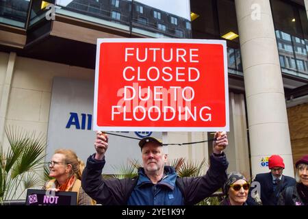 London, Großbritannien. Oktober 2024. Ein Aktivist hält vor den Büros der Allianz ein Schild mit der „Zukunft aufgrund von Überschwemmungen geschlossen“, während die Extinction Rebellion drei Tage lang Proteste in der City of London, dem Finanzviertel der Hauptstadt, in dem die Versicherungsgesellschaften aufgefordert werden, die Versicherung von Projekten mit fossilen Brennstoffen einzustellen. Quelle: SOPA Images Limited/Alamy Live News Stockfoto