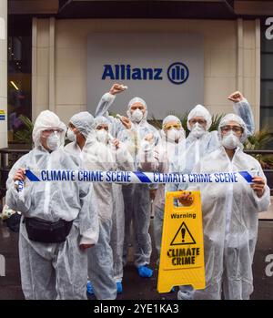 London, Großbritannien. Oktober 2024. Aktivisten in Gefahrenanzügen halten ein „Climate Crime Scene“-Band vor den Büros der Allianz, während die Extinction Rebellion drei Tage lang Proteste in der City of London, dem Finanzviertel der Hauptstadt, anfängt, Versicherungsgesellschaften aufzufordern, die Versicherung von Projekten mit fossilen Brennstoffen einzustellen. Quelle: SOPA Images Limited/Alamy Live News Stockfoto