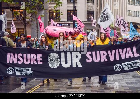 London, Großbritannien. Oktober 2024. Aktivisten marschieren mit einem „Versichern Sie unser Überleben“-Banner, während die Extinction Rebellion drei Tage lang Proteste in der City of London, dem Finanzviertel der Hauptstadt, anbricht und Versicherungsunternehmen auffordert, die Versicherung von Projekten mit fossilen Brennstoffen einzustellen. Quelle: SOPA Images Limited/Alamy Live News Stockfoto