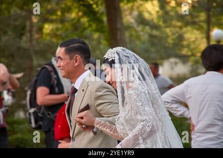 Buchara, Usbekistan; 19. September 2024: Ein romantischer Moment, in dem Jungvermählte durch die alten Straßen von Buchara, Usbekistan, schlendern. Stockfoto