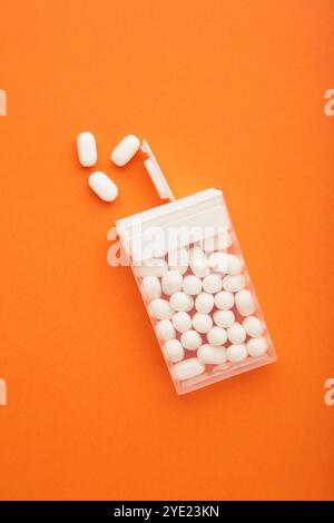 Leckere Minzbonbons mit Box auf orangem Hintergrund, Draufsicht Stockfoto