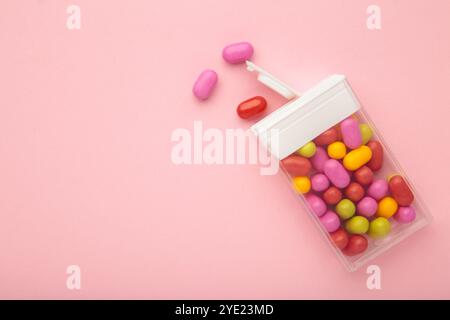 Leckere farbige Fruchtdragee Bonbons mit Box auf rosa Hintergrund, Blick von oben Stockfoto