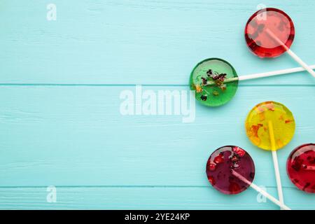 Bunte süße Lutscher mit Beeren auf blauem Hintergrund. Draufsicht Stockfoto