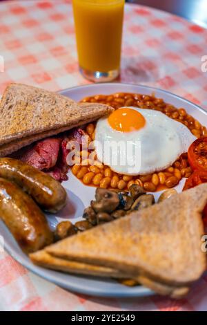 Englisches Frühstück mit Spiegeleiern, Würstchen, Speck, Bohnen, Toast und Tomaten Stockfoto