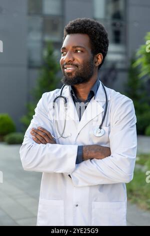 Mann Doktor, der im Krankenhaus steht, mit weißem medizinischem Kleid und Stethoskop Stockfoto