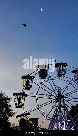 Flacher Blick auf die Ferris oder das Wunderrad im Schatten der Silhouette vor dem Himmel der Dämmerung auf dem Thai Red Cross Fair Night Market, Vergnügungsgebiet und Karneval Stockfoto