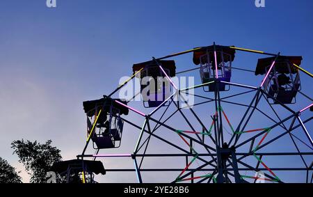 Flacher Blick auf die Ferris oder das Wunderrad im Schatten der Silhouette vor dem Himmel der Dämmerung auf dem Thai Red Cross Fair Night Market, Vergnügungsgebiet und Karneval Stockfoto