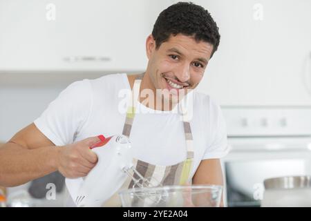 Ein glücklicher Mann, der den Teigmixer benutzt Stockfoto