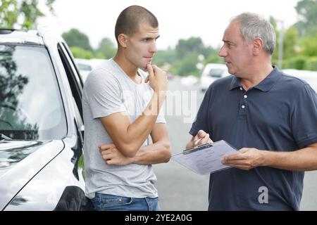 Fahrschüler mit Kursleiter, der vor der Fahrprüfung Formulare ausfüllt Stockfoto