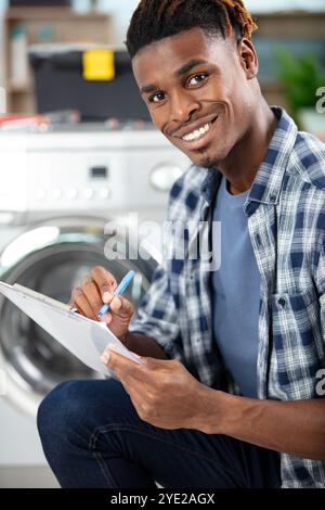 Männlicher Techniker sitzt in der Nähe des Geschirrspülers Stockfoto