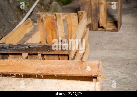 Holzkiste auf einem Betonboden mit Steinmauerhintergrund. Palettenkiste aus Holz. Die Kiste ist leer und aus Holz. Alt und abgenutzt Stockfoto