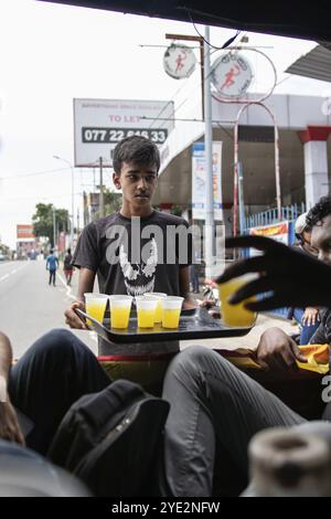 COLOMBO, SRI LANKA: 9. Juli 2022: Porträt eines ortsansässigen srilankischen Mannes, der einer Gruppe von Menschen auf dem Rücksitz eines Pickup während des Massenprotests Getränke serviert Stockfoto