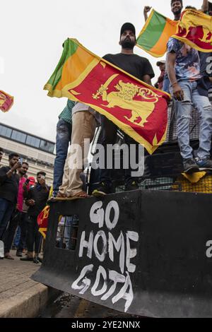 COLOMBO, SRI LANKA: 9. Juli 2022: Demonstranten stehen auf der Vorderseite eines Polizeiwagens, das die Nationalflagge über dem Schild hält, das darauf steht, nach Hause zu gehen Gota Stockfoto