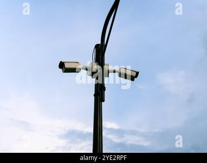 CCTV-Kameras, die an einem Stab gegen einen bewölkten Himmel montiert sind. Stockfoto