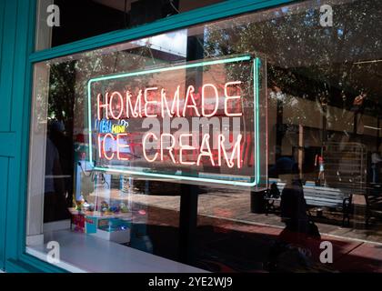 Neon Shop Schild im Ladenfenster „hausgemachte Eiscreme“ in Old Town, Kissimmee, Florida im Oktober 2024 mit einer Reflexion der Käufer, die vorbeigingen. Stockfoto