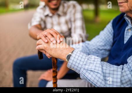 Nahaufnahme der Hand des jungen Mannes, der die Hand eines älteren Mannes hält. Stockfoto