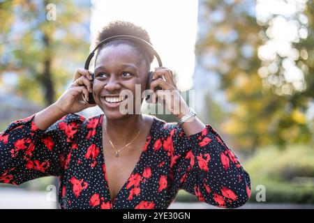 Junge Frau, die Musik mit Kopfhörern in der Stadt hört Stockfoto