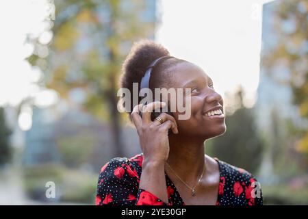 Junge Frau, die Musik mit Kopfhörern in der Stadt hört Stockfoto