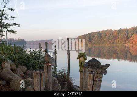 Morgennebel über der ruhigen Straussee mit einer einzigartigen Anordnung von Tierskulpturen, darunter ein Frosch, ein Fisch und eine Ente. Stockfoto