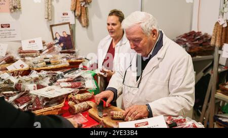 Besucher erkunden Stände mit lokalen Köstlichkeiten und handwerklichen Produkten beim Alba Truffle Festival in Italien. Zwei Anbieter arbeiten mit den Teilnehmern zusammen Stockfoto