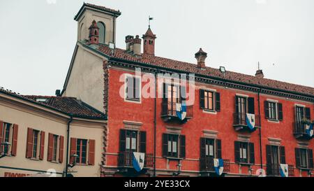 Dieses charmante Gebäude verfügt über eine leuchtend rote Fassade mit Fahnen, die eine malerische Atmosphäre in Alba schafft Stockfoto