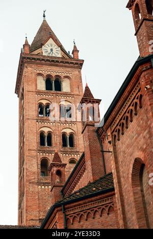 Der hoch aufragende Glockenturm einer historischen Kirche in Alba, Italien, steht mit detailliertem Mauerwerk und dekorativen Elementen markant am Himmel Stockfoto