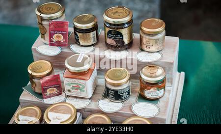 Verschiedene Gläser mit Honig und Konfitüren sind auf Holzregalen angeordnet, die lokale Aromen in Alba Italien zeigen. Die Marktatmosphäre verbessert den Stockfoto