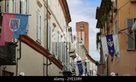 Im Herzen von Alba, Italien, zeigt eine alte Gasse wunderschöne Architektur mit bunten Bannern, die einen Einblick in die reiche Geschichte der Städte zeigen Stockfoto