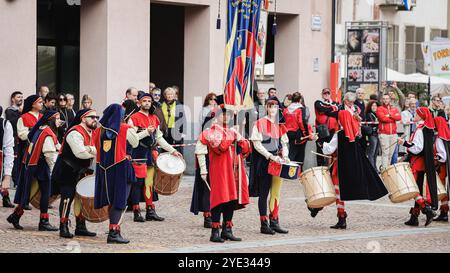 Teilnehmer in lebhaften Kostümen marschieren durch die Straßen von Alba, Italien, spielen Trommeln und feiern lokale Traditionen während der Frühlingsfeste, c Stockfoto