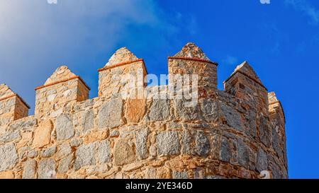 Avila, Spanien - 11. Februar 2023: Hoher Teil einer mittelalterlichen befestigten Mauer vor einem blauen Himmel. Stockfoto