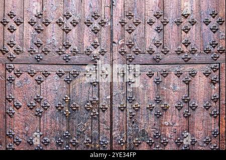 Avila, Spanien - 11. Februar 2023: Muster von dekorativen Nieten auf der Holzoberfläche einer mittelalterlichen Eingangstür. Stockfoto