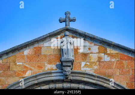 Avila, Spanien - 11. Februar 2023: Religiöses Kreuz und dekorative heilige Statue im oberen Teil der Pfarrei St. Peter dem Apostel. Stockfoto