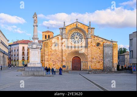 Avila, Spanien - 11. Februar 2023: Touristen auf dem Platz bei der Pfarrei St. Peter dem Apostel, mit einer orangefarbenen Steinfassade. Stockfoto