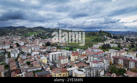 Ein Panoramablick auf Alba offenbart die bezaubernde Stadt, umgeben von sanften Hügeln. Wohnhäuser mit roten Dächern stehen im Kontrast zum üppigen Grün, Stockfoto