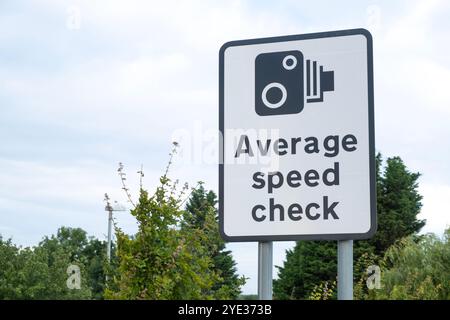 Großes Straßenschild, das den Autofahrer darauf hinweist, dass die Strecke vor der Autobahn eine Zone mit durchschnittlicher Geschwindigkeitskontrolle ist. Stockfoto