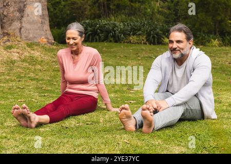 Reifes Paar, das sich auf dem Gras ausdehnt und gemeinsam Outdoor-Bewegung und Entspannung genießt Stockfoto