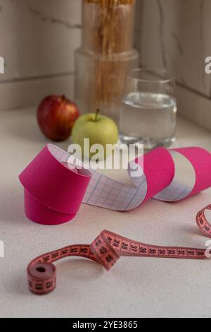 Pinkfarbenes kinesio-Klebeband mit einem Maßband auf weißem Hintergrund Stockfoto