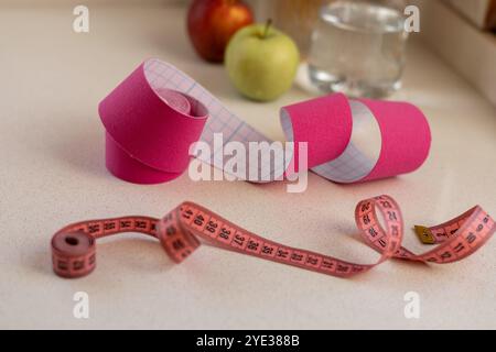 Pinkfarbenes kinesio-Klebeband mit einem Maßband auf weißem Hintergrund Stockfoto